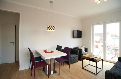 a living room with a table and chairs and a couch at Apartment Eisberg 6 mit Balkon in Norderney
