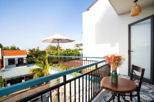 a balcony with a table and chairs and a pool at 5 Coconut Villa in Hoi An