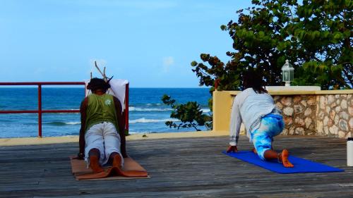 two people are doing yoga on a boardwalk at Taino Cove in Treasure Beach