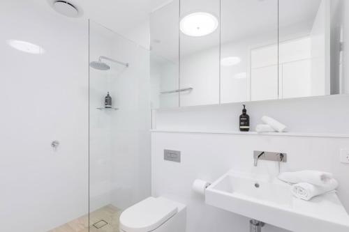 a white bathroom with a toilet and a sink at 13 First Avenue Sawtell in Sawtell
