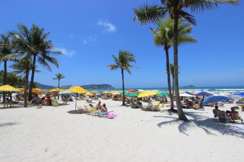 un grupo de personas sentadas en la playa con sombrillas en Hotel Ilhas do Caribe - Na melhor região da Praia da Enseada en Guarujá