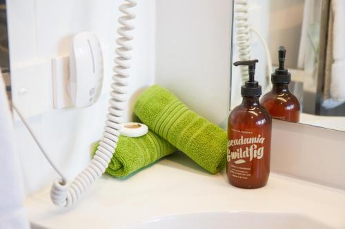 a bathroom sink with a bottle of soap and towels at 850 Cameron Motel in Tauranga