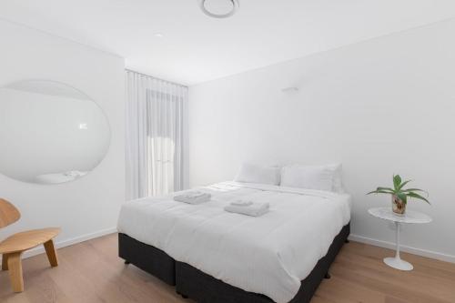 a white bedroom with a large bed and a table at 13 First Avenue Sawtell in Sawtell