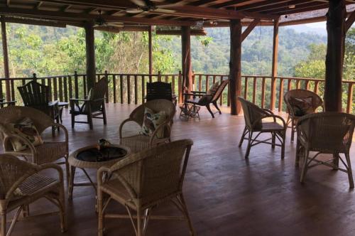 a porch with chairs and tables on a deck at Wanakaset Forest Glamping in Kitulgala