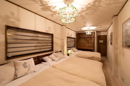 a room with three beds and a chandelier at AGURIHOME Hayashiji in Osaka