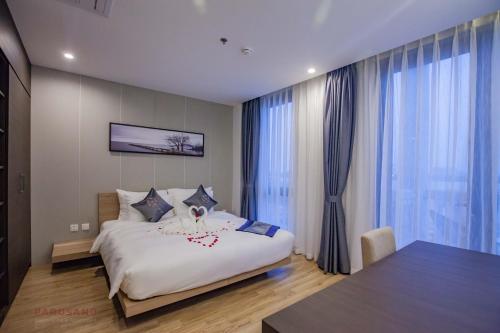 a bedroom with a large white bed and large windows at Parosand Hanoi Hotel in Hanoi