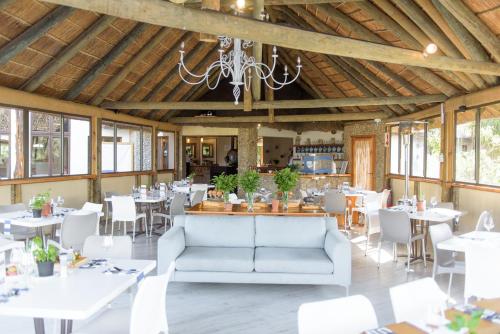 a dining room with tables and chairs and a chandelier at Whalesong Hotel & Spa in Plettenberg Bay