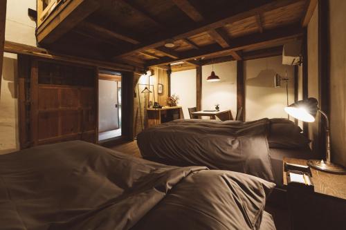 a bedroom with two beds and a lamp and a table at NIPPONIA Kosuge Village in Kosuge
