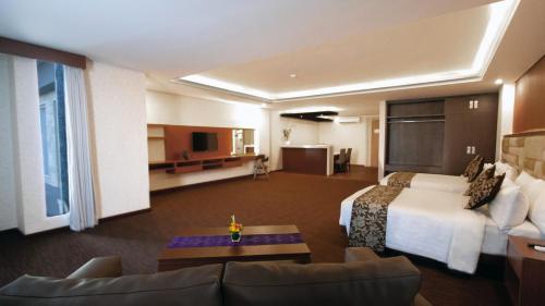 a hotel room with a bed and a living room at Quest San Denpasar by ASTON in Denpasar