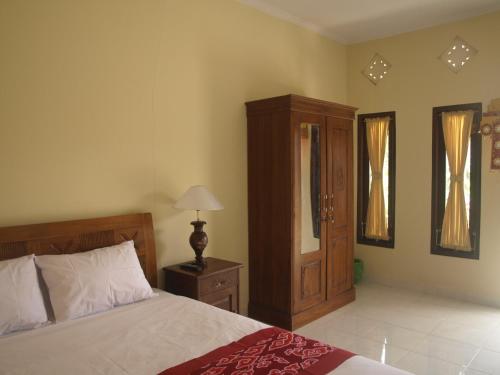 ein Schlafzimmer mit einem Bett, einem Schrank und einer Lampe in der Unterkunft D'SARI UNDISAN Houses in Bangli