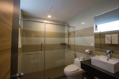 a bathroom with a shower and a toilet and a sink at Mariner Hotel Labuan in Labuan