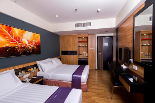 a hotel room with two beds and a tv at Mariner Hotel Labuan in Labuan