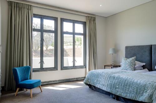 a bedroom with a bed and a blue chair and windows at House 217 in Nottingham Road