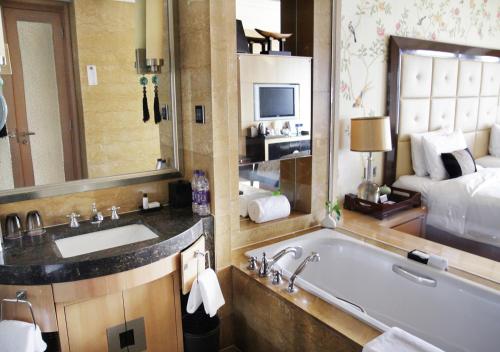 a bathroom with a tub, sink, and mirror at Wanda Vista Beijing in Beijing