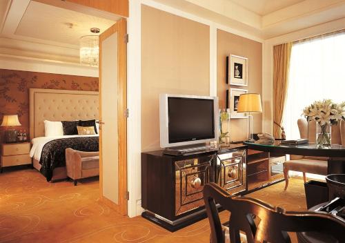a hotel room with a tv, coffee table and a desk at Wanda Vista Beijing in Beijing