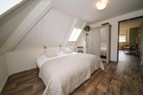 ein Schlafzimmer mit einem großen weißen Bett im Dachgeschoss in der Unterkunft Gastenverblijf Eenigenburg in Eenigenburg