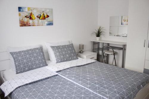 um quarto com uma cama com roupa de cama cinzenta e branca em Apartman TIM em Osijek