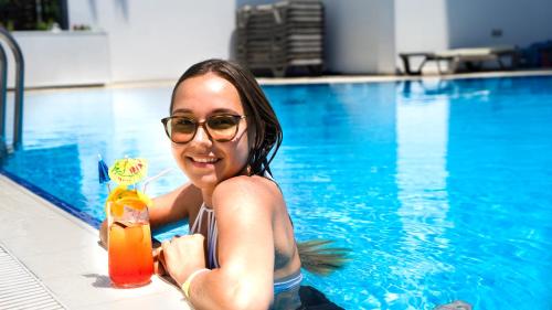 Eine Frau im Schwimmbad, die einen Drink hält. in der Unterkunft CihanTürk Hotel in Marmaris