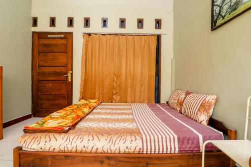 a bedroom with a bed and a door with a window at Nabhan Homestay in Kalirejo
