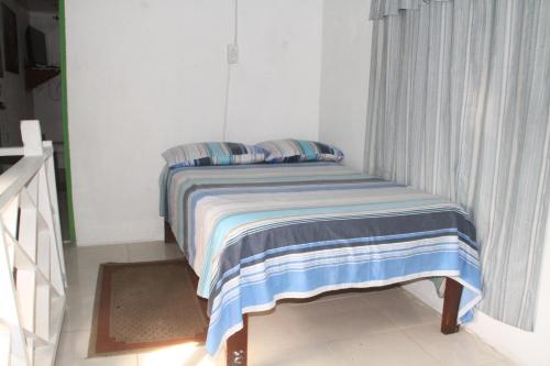 a small bed with a striped blanket in a bedroom at Posada green sea villa helen kilometro 4 circumbalar in Buenavista