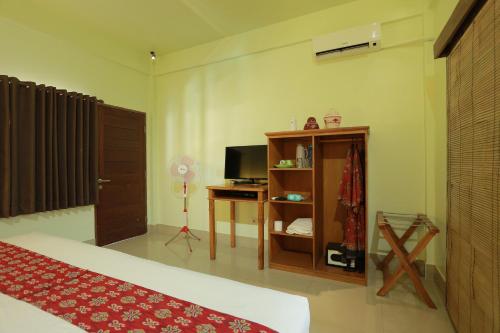a bedroom with a bed and a desk and a television at Trawangan Nirvana in Gili Trawangan