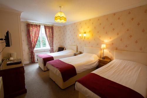 a hotel room with two beds and a chandelier at Fines Bayliwick Hotel in Bracknell