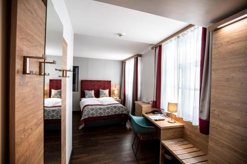 Habitación de hotel con cama y escritorio. en Hotel Elefant Family Business en Salzburgo