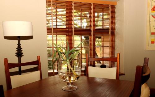 una mesa de comedor con un jarrón de cristal. en Sherewood Lodge, en Pretoria