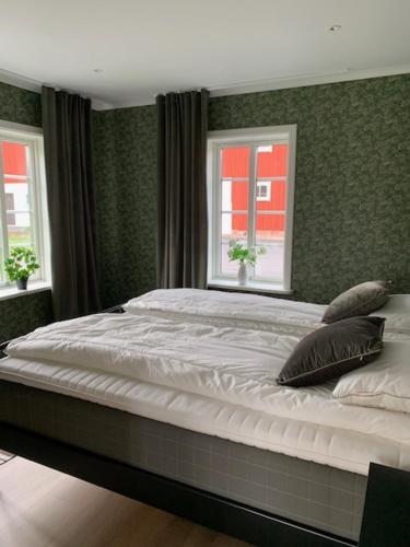 a bedroom with a large bed with two windows at Ollestad gård in Ljung