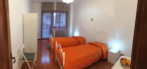 two beds in a bedroom with an orange blanket at Da noi. Nella città dell'acqua e della pietra. in Gravina in Puglia