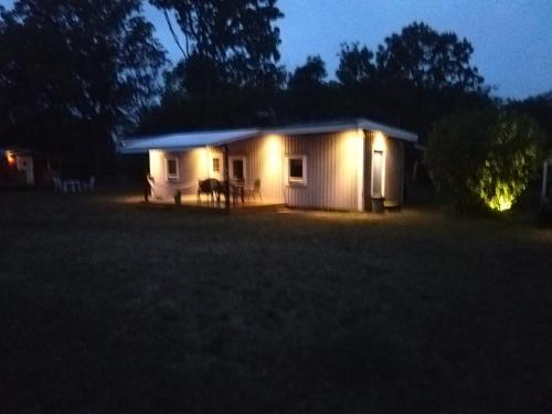 a small white house with lights in the dark at Kvarngården Natur Resort in Byxelkrok
