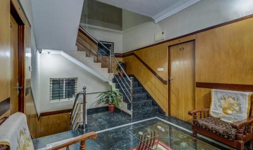a hallway with a staircase and a chair and a stair case at Itsy Hotels Shree Comforts in Bengaluru