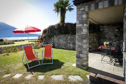 two chairs and an umbrella sitting in a yard at La Collina dei Fiori in Vercana