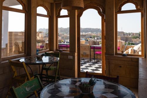 Habitación con mesa, sillas y ventanas. en The Secret House - Adults Only en Jaisalmer