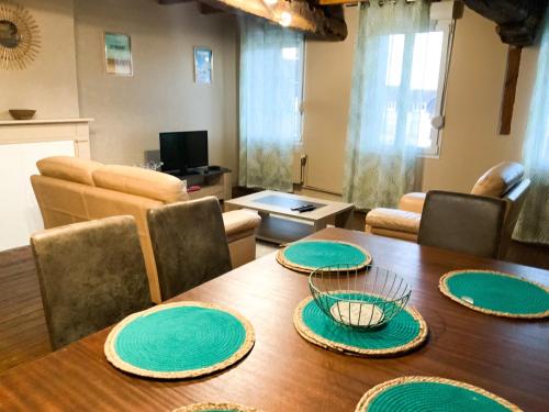 Grand appartement idéalement situé 7 places في Desvres: غرفة طعام مع طاولة عليها لوحات خضراء