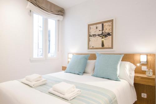 1 dormitorio blanco con 1 cama grande con almohadas azules en Pelayo, 8, en Madrid