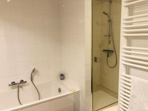 a bathroom with a shower and a bath tub with a glass door at EastDune in Oostduinkerke