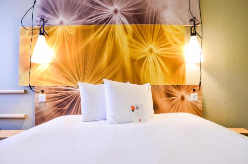 a bed with two pillows in a hotel room at ibis Hotel Frankfurt Airport in Kelsterbach