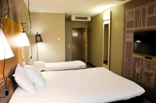 a hotel room with two beds and a flat screen tv at ibis Hotel Frankfurt Airport in Kelsterbach