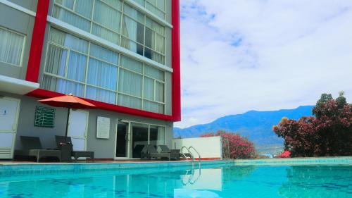 a hotel with a swimming pool in front of a building at Hotel Santika Palu in Palu