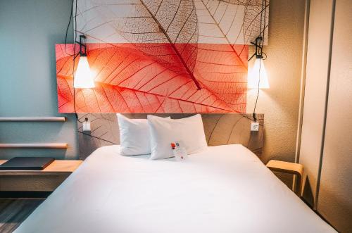 a bedroom with a large white bed with two pillows at ibis Hotel Frankfurt Airport in Kelsterbach