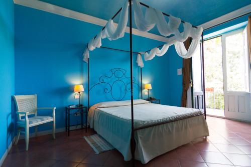 a bedroom with a canopy bed in a blue room at Etna Hotel in Giarre