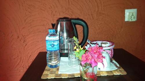 a table with a tea kettle and a bottle of water at Hotel Hideaway Garage in Dambulla