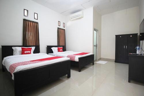 1 dormitorio con 2 camas con sábanas rojas y blancas en OYO 1547 Wisma Ray Syariah, en Lampung