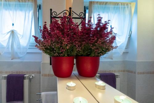 two red vases with flowers on top of a table at La Collina degli Ulivi in Vercana