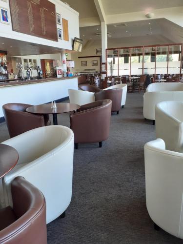 a restaurant with brown and white chairs and tables at Weald of Kent Golf Course and Hotel in Maidstone