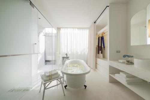 a white bathroom with a tub and a chair in it at Sala Lanna Chiang Mai in Chiang Mai