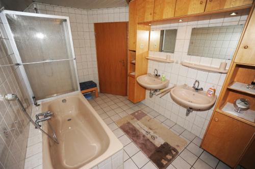 a bathroom with two sinks and a tub and a shower at Ferienwohnung Schilling_ 65043 in Moormerland