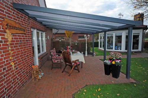 a patio with a blue canopy and a table and chairs at Ferienwohnung Schilling_ 65043 in Moormerland