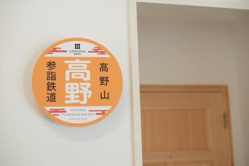 an orange and white sign on a door at Nipponia Hotel Koyasan Pilgrimage Railway - In the station Inn - Self Check-In Only in Kudoyama